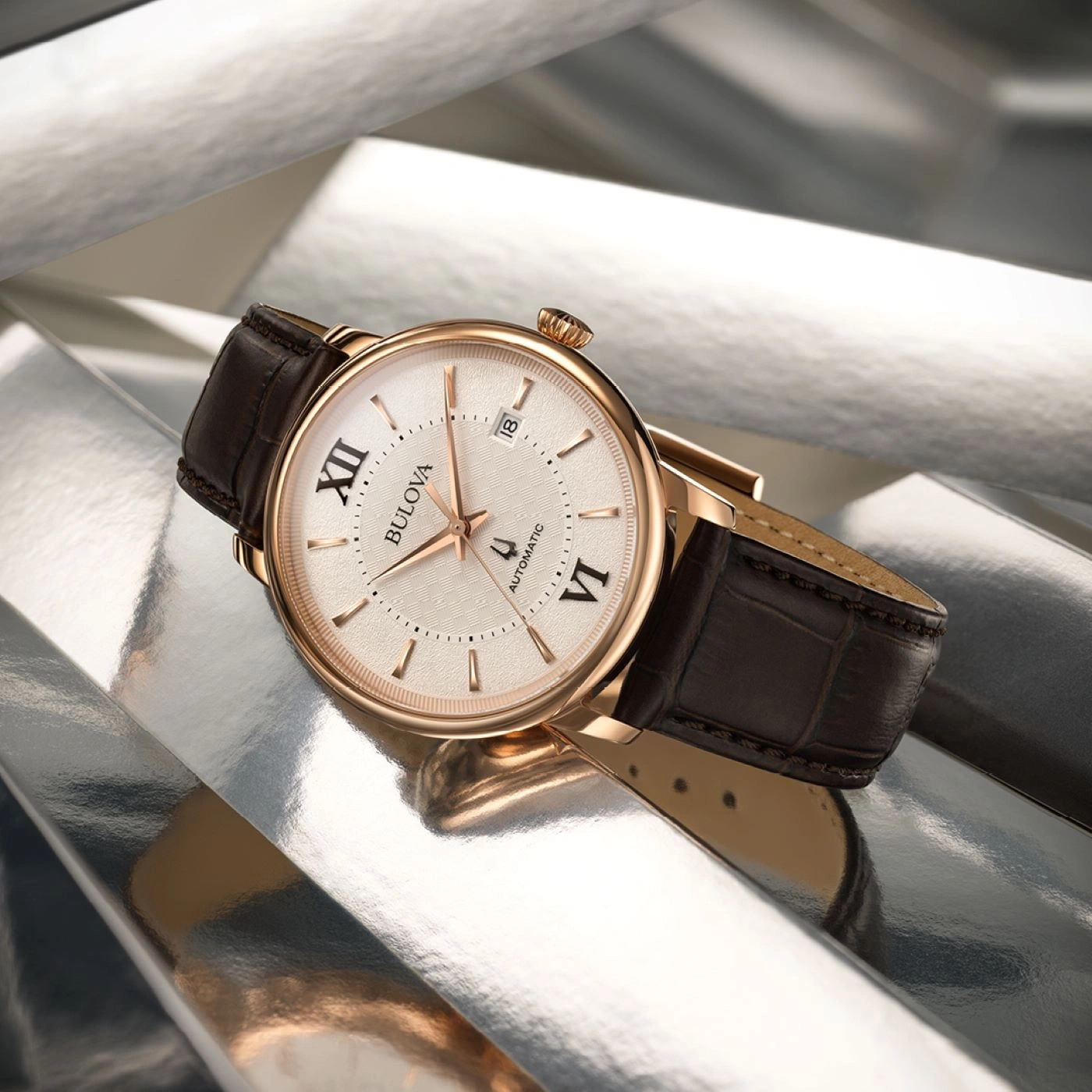 Gouden Bulova horloge met bruine leren band op zilveren achtergrond.