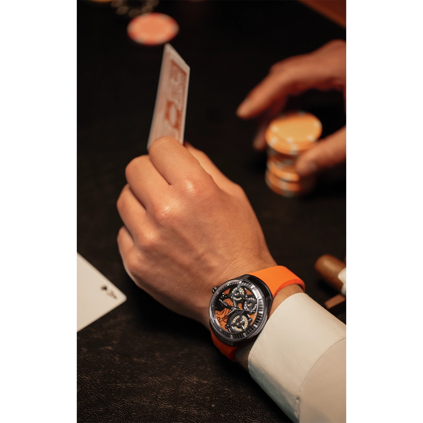 Man speelt poker met horloge, kaarten en chips in de hand.