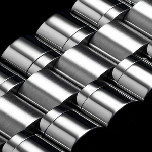 Close-up van glanzend metalen oppervlak met gebogen elementen en reflecties op zwart
