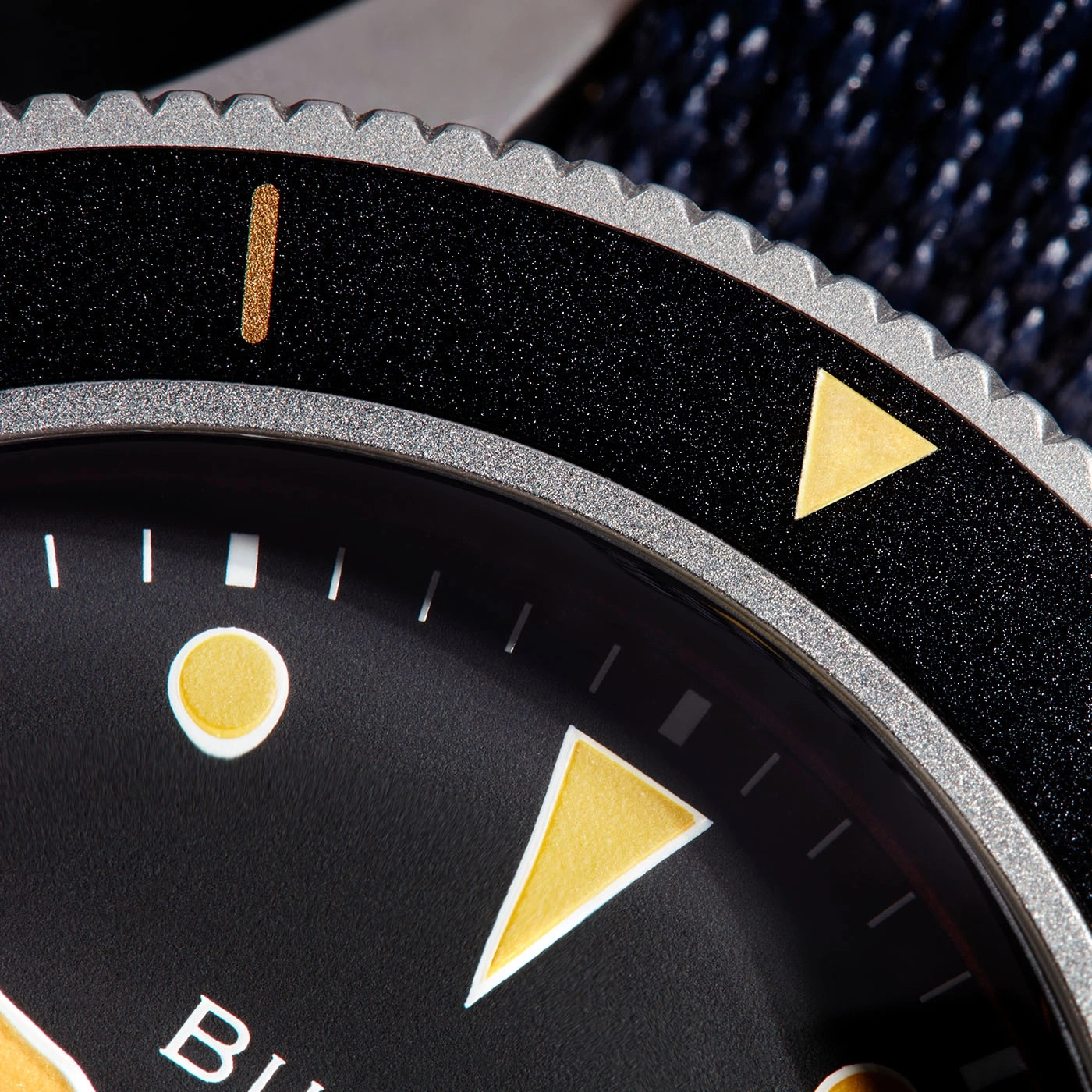 Close-up van een zwarte horloge met gouden accenten en details.