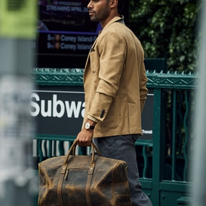 Man met jas en tas bij metro-ingang. Onderweg naar de stad.