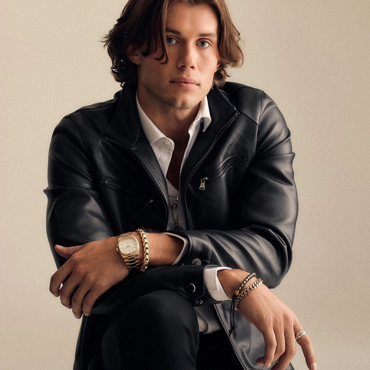 Man in leren jas met horloge en sieraden, zelfverzekerde pose