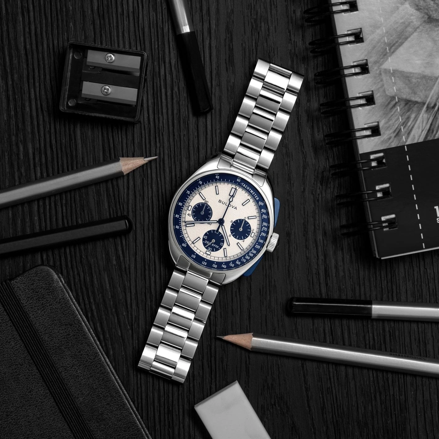 Horloge, pennen, notitieboek en gum op zwart hout. Bulova horloge.