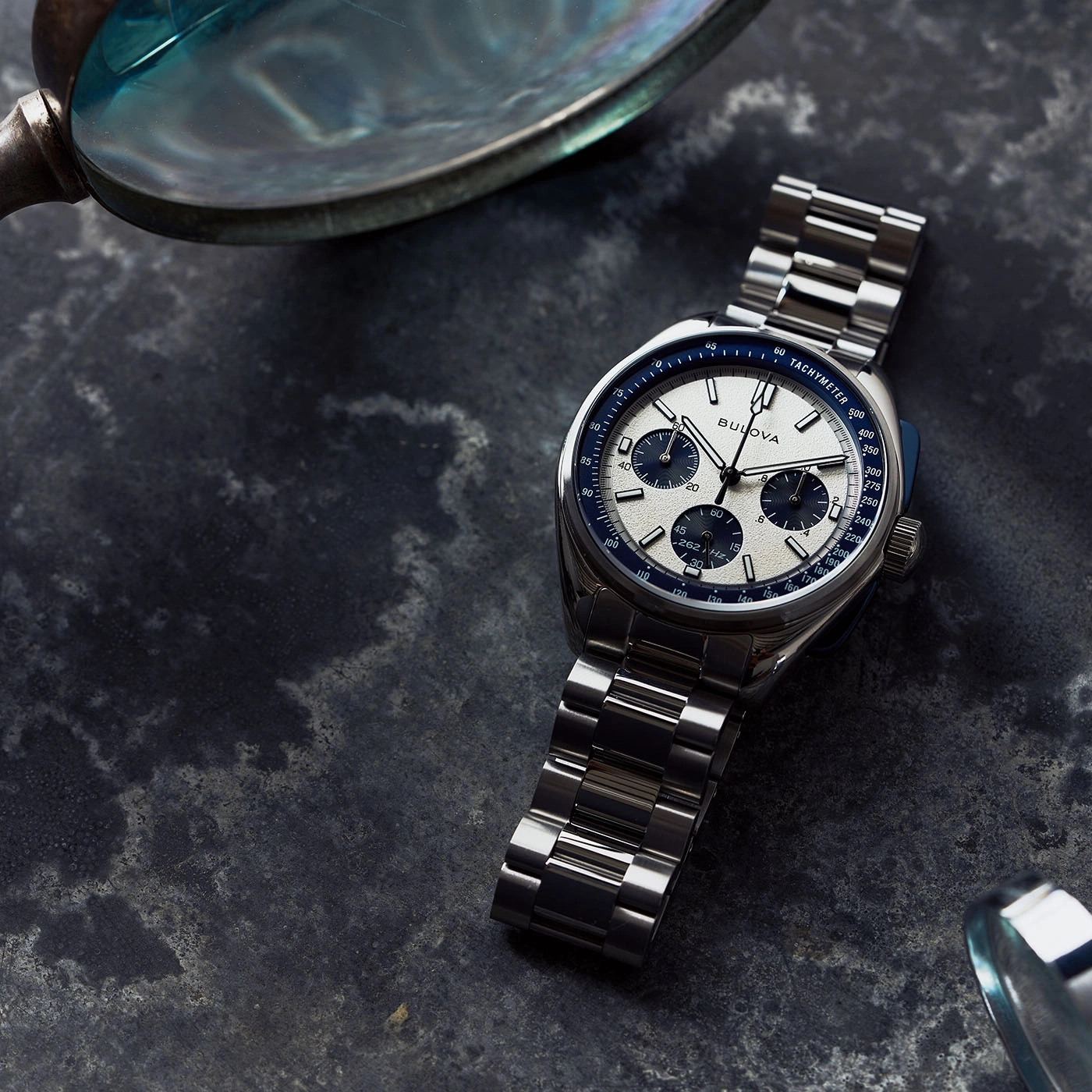 Horloge met metalen band en tachymeter op donkere achtergrond, close-up.