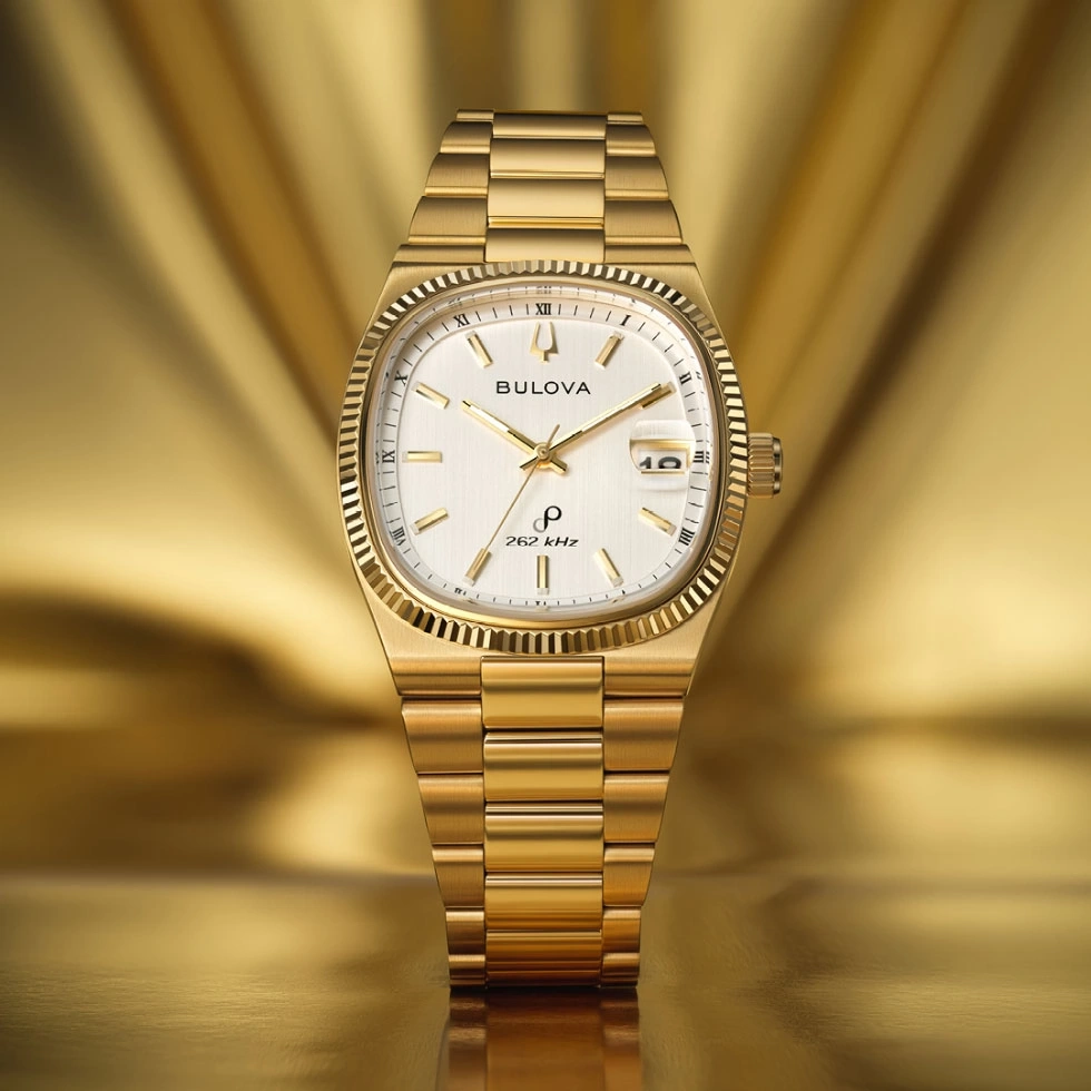 Gouden Bulova horloge met witte wijzerplaat en gouden armband.