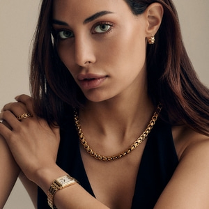 Portret van een vrouw met sieraden, die in de camera kijkt, met ketting en horloge.