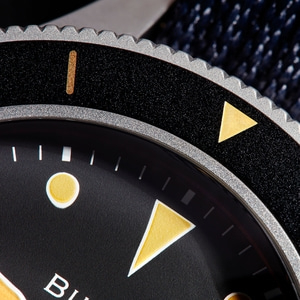 Close-up van een zwarte horloge met gouden accenten en details.