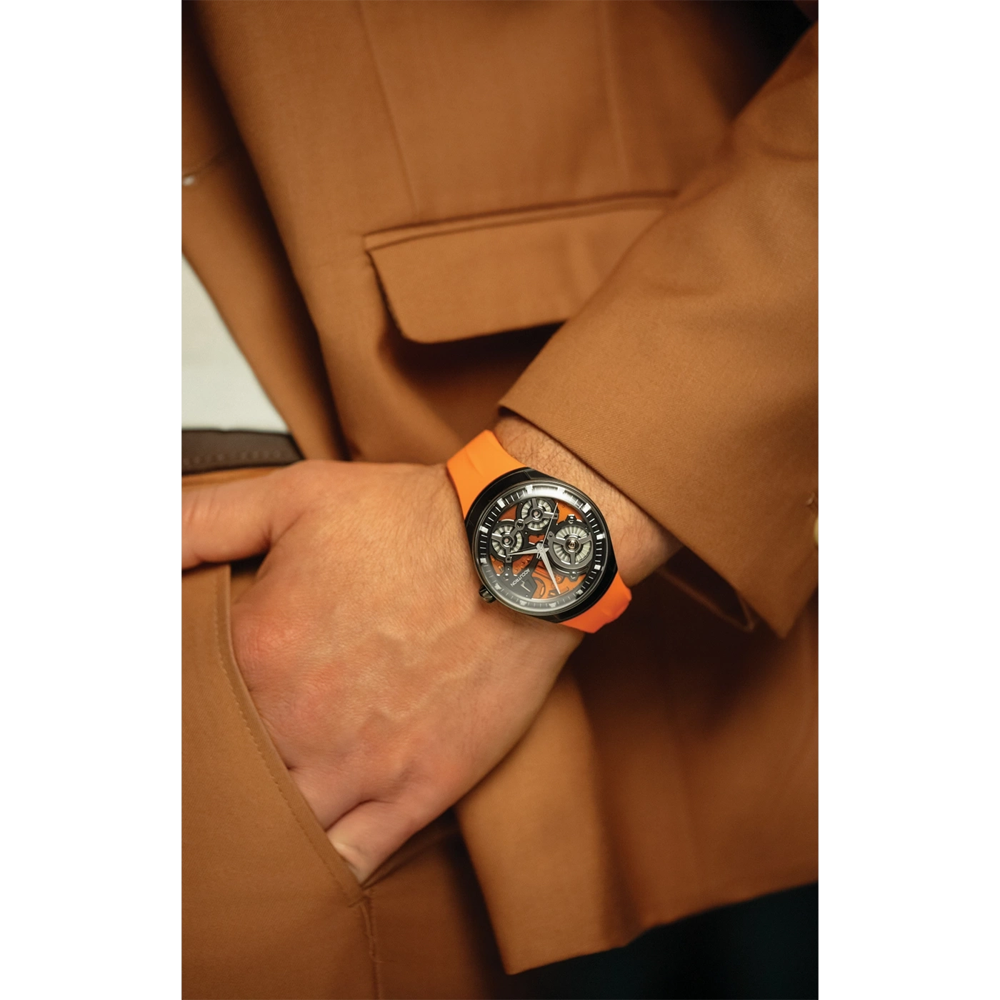 Man met horloge en oranje band in bruin jasje