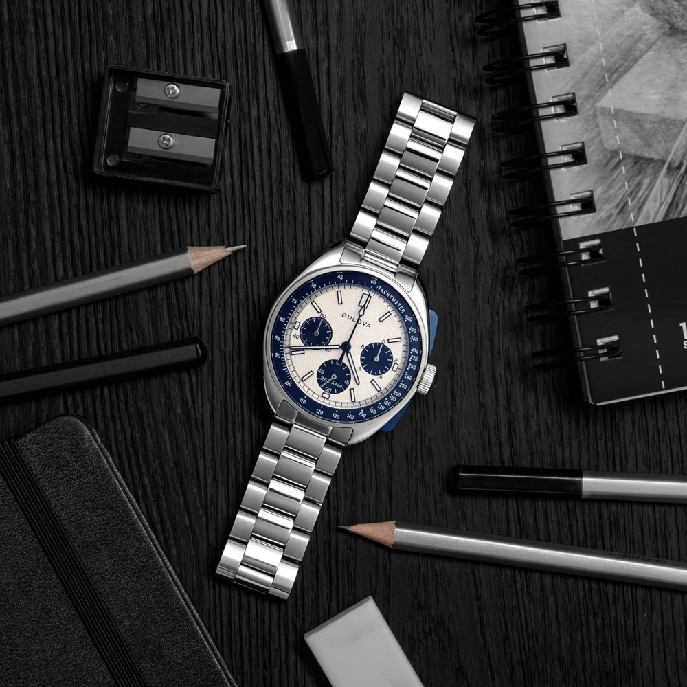 Horloge, pennen, notitieboek en gum op zwart hout. Bulova horloge.