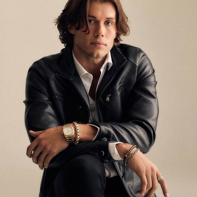 Man in leren jas met horloge en sieraden, zelfverzekerde pose