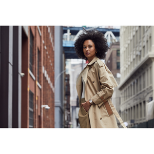 Vrouw in beige trenchcoat in de stad, kijkt in de camera, mode