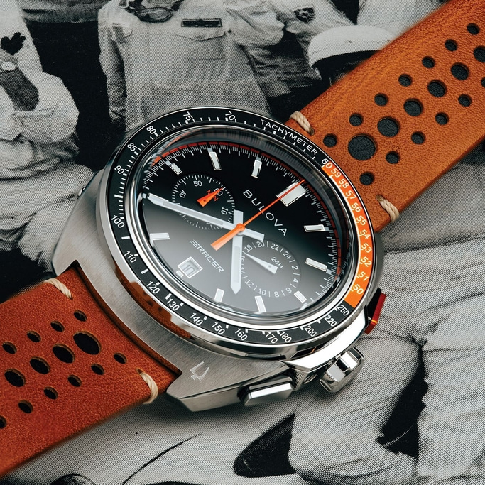Een Bulova horloge met zwarte wijzerplaat en oranje band op een achtergrond.