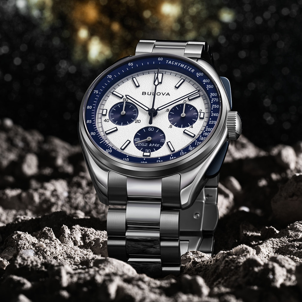 Bulova horloge op rotsachtige ondergrond met blauwe wijzerplaat en zilveren armband.