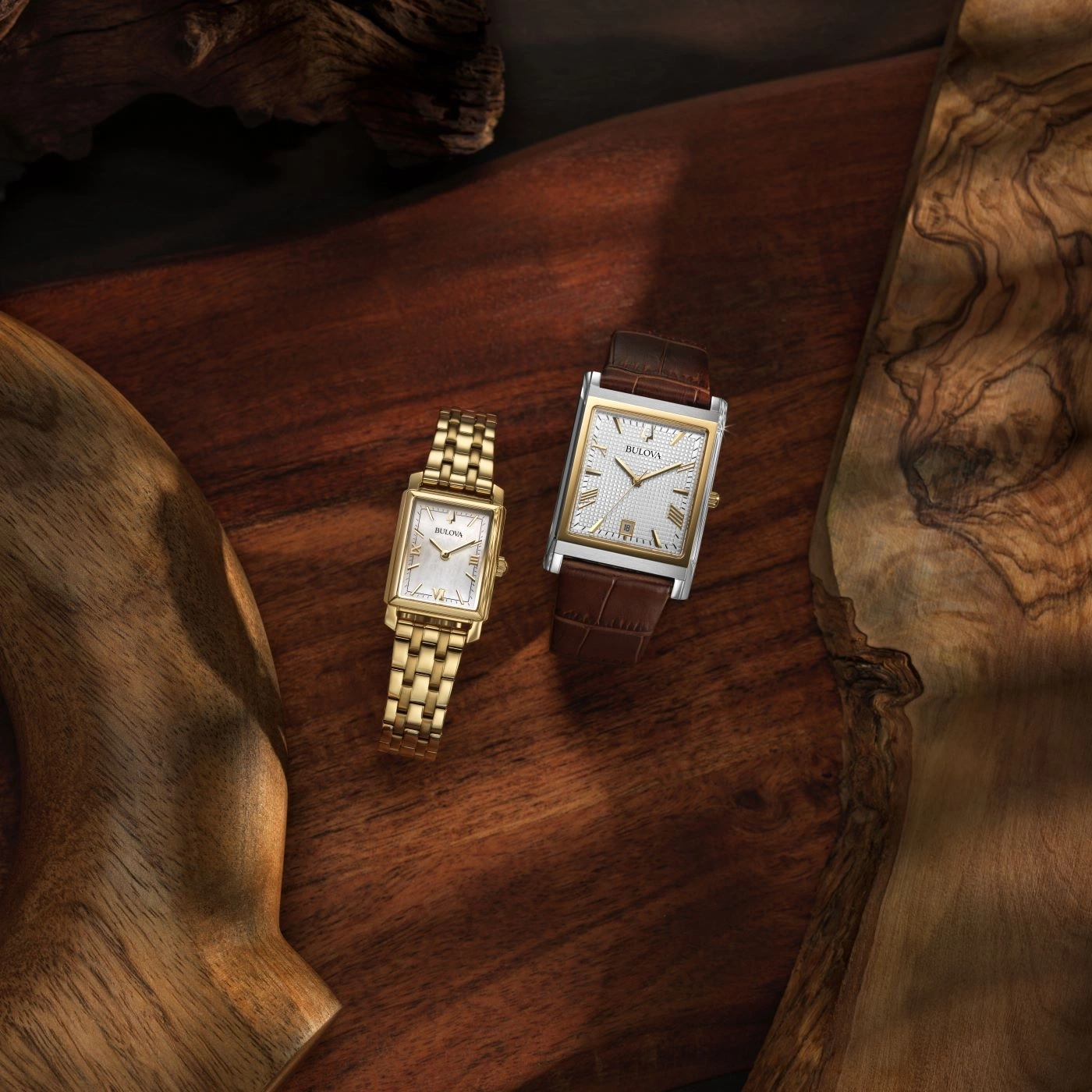 Twee Bulova horloges op houten plank, goud en bruin, elegant design.