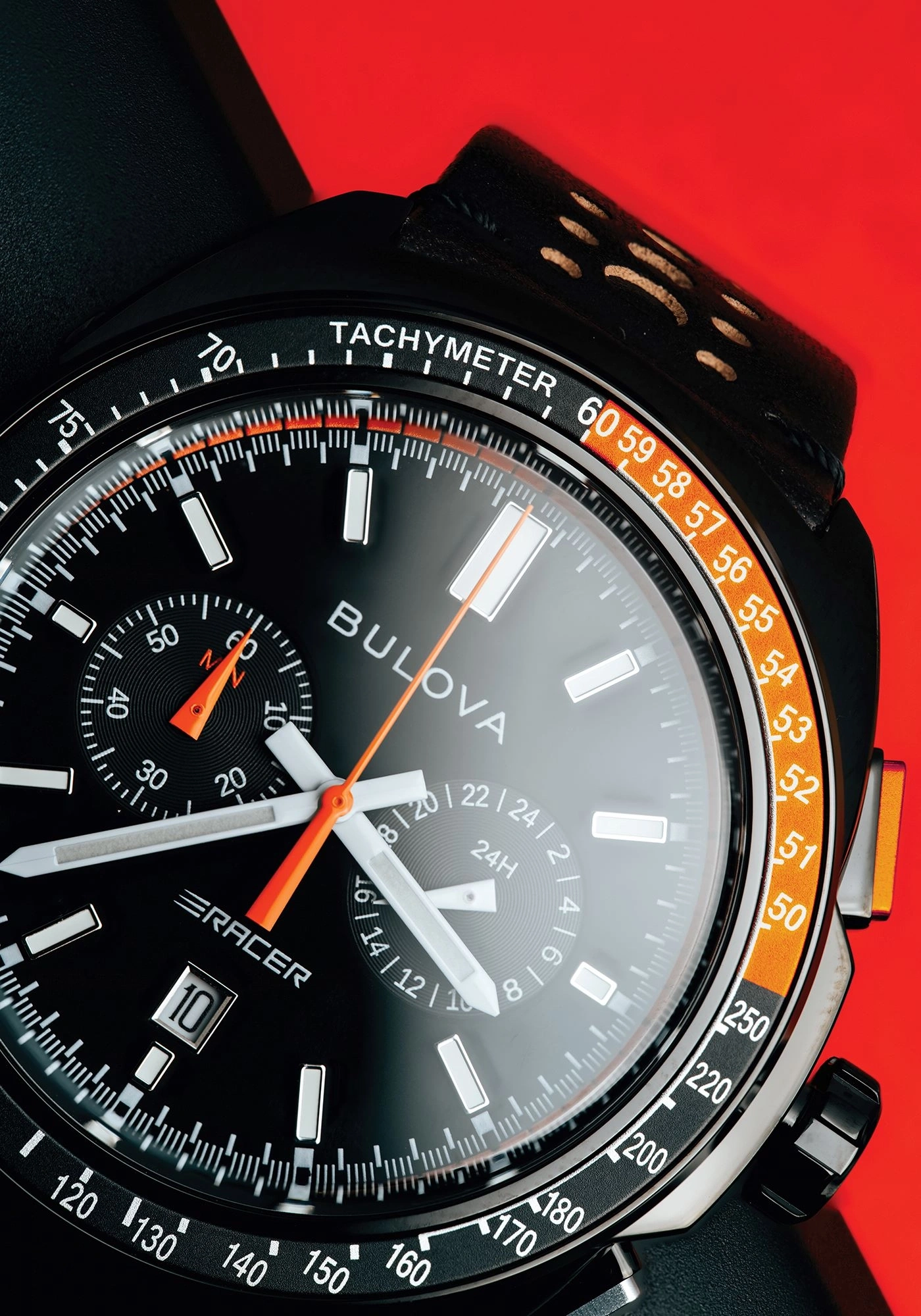Close-up van een Bulova horloge met zwarte wijzerplaat, tachymeterschaal en oranje accenten.