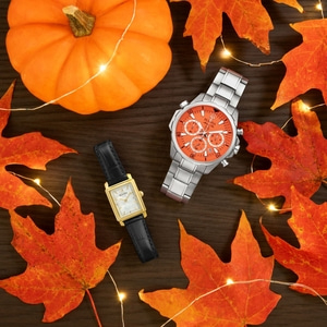 Herfsttafereel met pompoen, bladeren, horloges en lichtslingers op hout